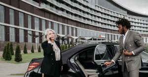 Chauffeur holding a car door open beside a business traveller