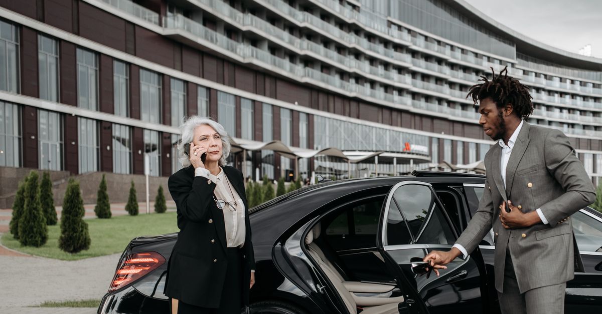 Chauffeur holding a car door open beside a business traveller