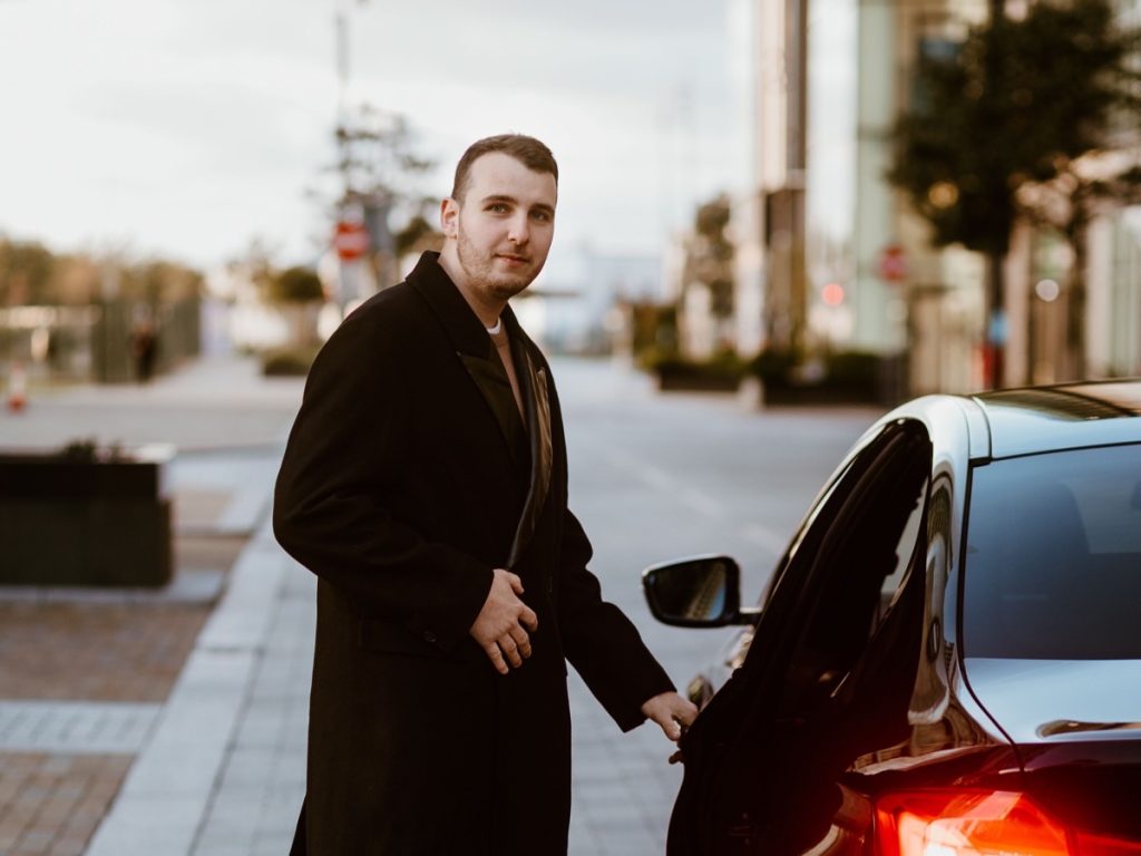 Well-dressed man opening a luxury car door in the city